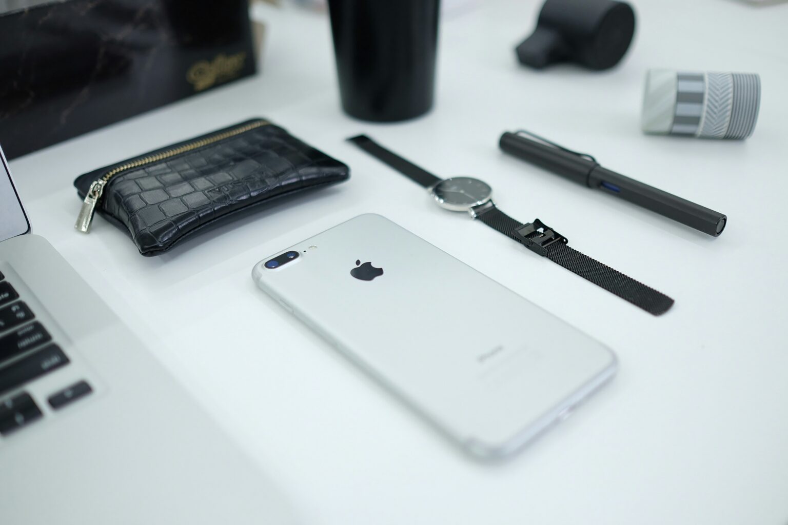A tidy desk with a phone, watch and pen