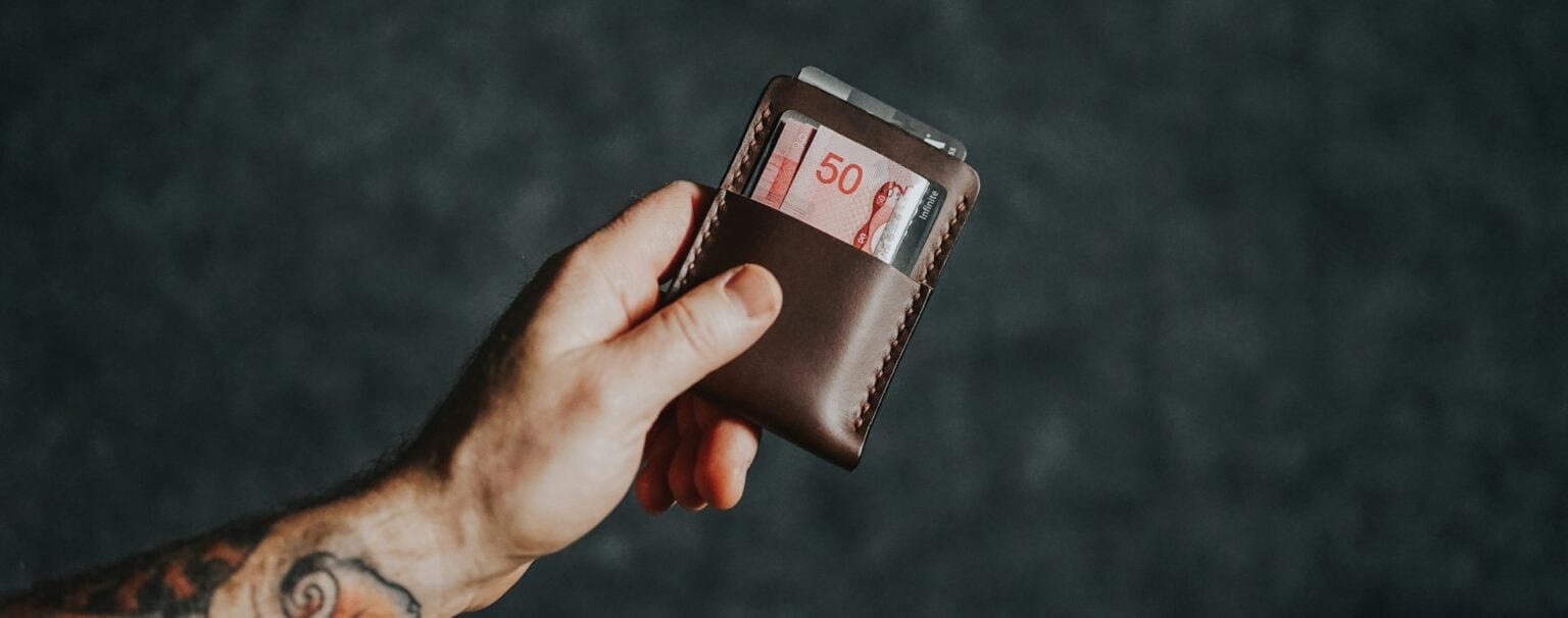 A man holding his wallet with a $50 note in it