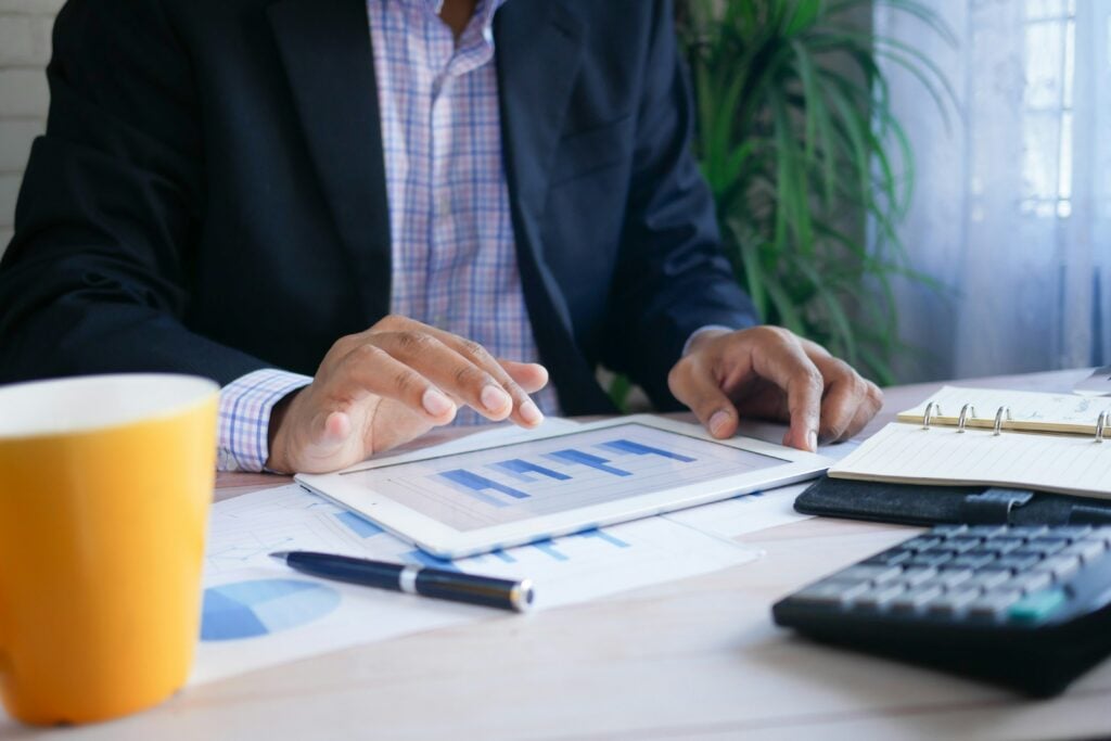 A man looking at a graph on his tablet device whilst sitting at a desk