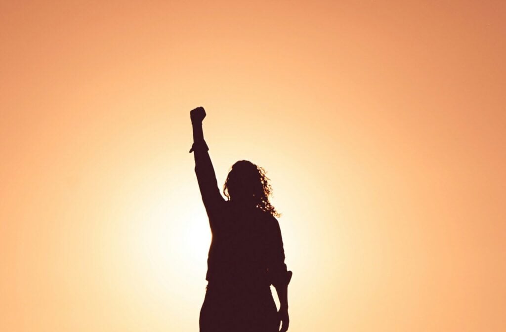 A person celebrating success in the sunrise