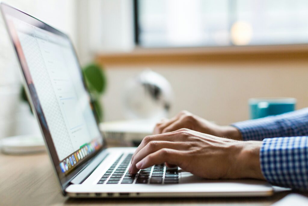 A man typing on his laptop whilst sitting at a desk